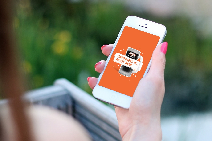 Girl holding phone in hand with 'Happiness is Root Beer' phone wallpaper