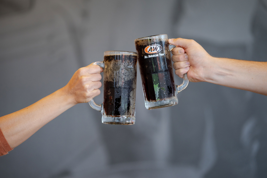 Two people toasting with mugs of A&amp;amp;W Root Beer