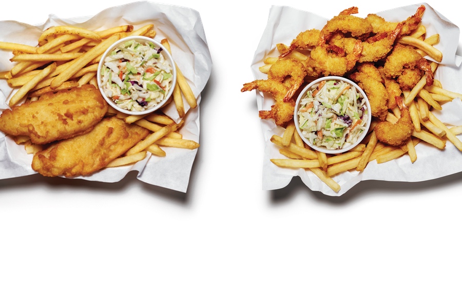 Overheard shot of two pub style baskets. One with cod, the other with shrimp. Both have fries and coleslaw.